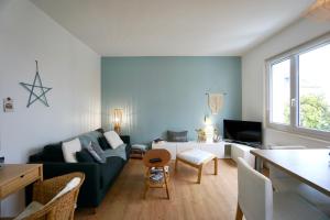 a living room with a green couch and a table at Le Bellevue *A 2 pas de la mer * Hyper centre* in Larmor-Plage