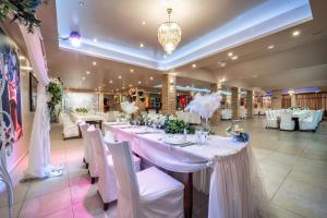 um salão de banquetes com uma longa mesa com cadeiras brancas em Hotel Rivera em Dobrich