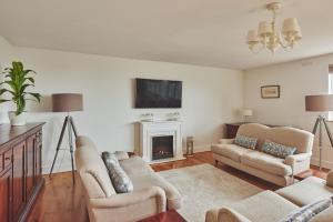 a living room with two couches and a fireplace at Ty Seren in Oxwich