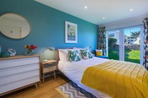 a blue bedroom with a bed and a mirror at Secret Beach in Carbis Bay