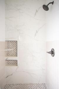 a bathroom with a shower with white marble walls at Cozy Studio - Blocks from the Ocean! in Jacksonville Beach