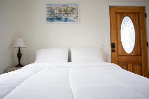 a bedroom with a white bed and a wooden door at Cozy Studio - Blocks from the Ocean! in Jacksonville Beach