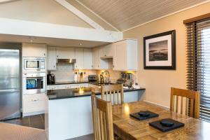 a kitchen with white cabinets and a wooden table at Cameron House Lodges in Balloch