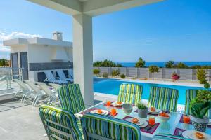- une table et des chaises sur une terrasse avec piscine dans l'établissement Villa Pleiades, à Peyia