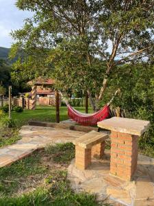 a hammock and a bench in a garden at Recanto das Flores in São Thomé das Letras