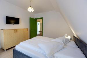 1 dormitorio con 1 cama blanca y TV en Pensiunea Joker en Sighişoara