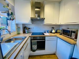 uma cozinha com armários brancos, um lavatório e um micro-ondas em Cloud9StayZ at The Oakridge em Woking