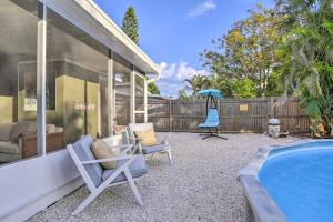 a patio with chairs and a swimming pool next to a house at Reddington Beach Oasis with Pool, Walk to Ocean! in St. Pete Beach