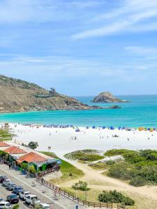 a beach with people on the sand and the water at Cobertura Luxo com Jacuzzi Orla Praia Grande in Arraial do Cabo