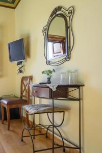 um toucador com um espelho e uma cadeira em Papigiotis Hotel em Tsepelovo
