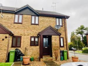 a brick house with a brown door and two green trash cans at Cloud9StayZ at The Oakridge in Woking