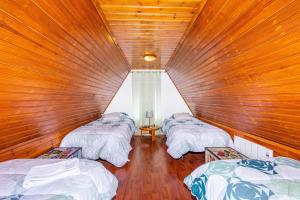 3 camas en una habitación con paredes de madera en Bangaló in Serra da Estrela, en Covilhã