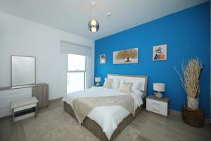 Dormitorio azul con cama y TV en Yas Island - 2 Bedrooms, 2 toilet with shared Pool & Parking en Abu Dabi