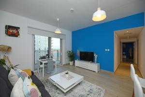 a living room with a couch and a blue wall at Yas Island - 2 Bedrooms, 2 toilet with shared Pool & Parking in Abu Dhabi