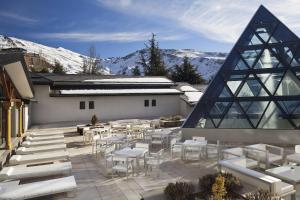 eine Terrasse mit weißen Tischen und Stühlen vor einem Gebäude in der Unterkunft Meliá Sol y Nieve in Sierra Nevada