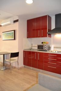 cocina con armarios rojos y mesa con microondas en Hotel Apartamentos Don Juan I, en Alcalá de Henares