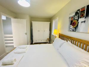 um quarto com uma cama grande e lençóis brancos em Cloud9StayZ at The Oakridge em Woking