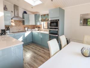 a kitchen with blue cabinets and a table with chairs at Windermere Lodge in Bowness-on-Windermere