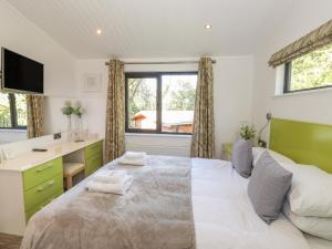 a bedroom with a large bed with a desk and a window at Windermere Lodge in Bowness-on-Windermere