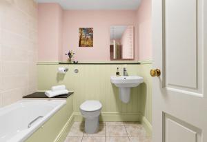 a bathroom with a toilet and a sink and a tub at The Neuadd Cottages in Crickhowell