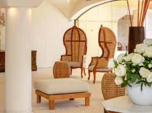 a room with chairs and a table with a vase of flowers at Hotel Costa dei Fiori in Santa Margherita di Pula