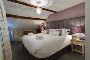 a bedroom with a large white bed and a chair at Acorn Cottage in Grasmere