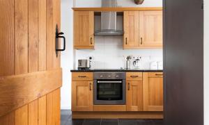 a kitchen with wooden cabinets and a stove top oven at Pollys Cottage in Elterwater