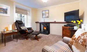 a living room with a fireplace and a television at Ghyll Foot Cottage in Ambleside