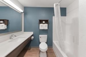 a bathroom with a toilet and a sink and a tub at WoodSpring Suites Dayton North in Dayton