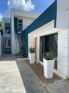 uma casa branca com dois vasos de plantas em frente em Work space Hostal em Uribia