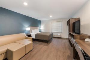 a hotel room with a bed and a couch and a television at WoodSpring Suites Dayton North in Dayton