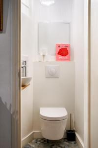 a bathroom with a white toilet and a book at Edgar Suites Montorgueil - Caire in Paris