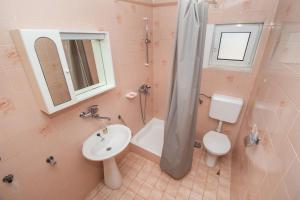 een badkamer met een wastafel, een toilet en een douche bij Apartments Nena in Tribunj