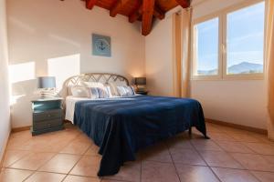 a bedroom with a bed with a blue bedspread and two windows at Residence SardegnaSummer Li Cuppulati in San Teodoro