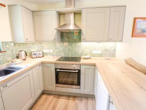 Una cocina con gabinetes blancos y un fregadero. en Ashness, en Ambleside