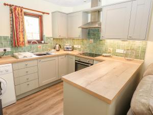 Una cocina con gabinetes blancos y una encimera de madera. en Ashness, en Ambleside 6 fotos más