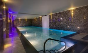 una piscina en una casa por la noche con luces moradas en Orrest Range, en Windermere