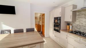 uma cozinha com armários brancos e uma bancada em Bowderstone em Keswick