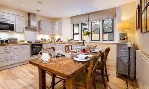 a kitchen with a wooden table and chairs in a kitchen at Deer Wood at Applethwaite Hall in Windermere