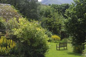 um banco de parque sentado no meio de um jardim em Thomas Cottage em Penrith