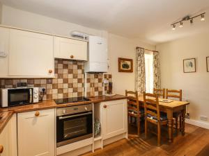 una cucina con mobili bianchi e un tavolo e una sala da pranzo di Jessicas Cottage a Bowness-on-Windermere Altre 6 foto