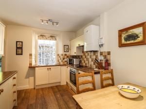 a kitchen with white cabinets and a wooden table at Jessicas Cottage in Bowness-on-Windermere