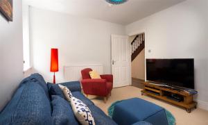 a living room with a blue couch and a tv at Ellerthwaite House in Windermere