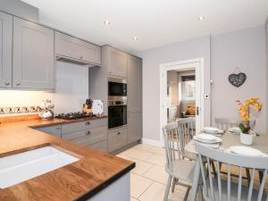 eine Küche mit weißen Schränken und einem Tisch und Stühlen in der Unterkunft Lakestone Cottage in Windermere