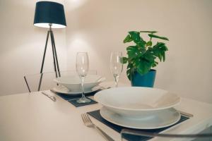 a table with two plates and glasses and a potted plant at Modern 2 Bed Apartment Near City Centre in Chelmsford