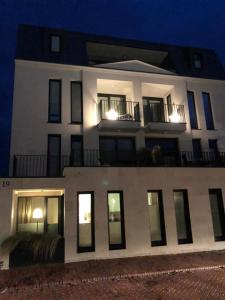 a large white building with windows at night at meerZEIT Norderney in Norderney
