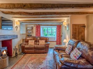 sala de estar con muebles de cuero y chimenea en Knotts Cottage, en Windermere