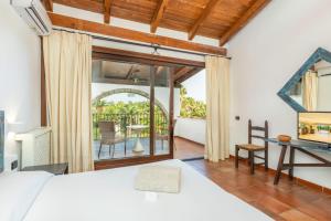 a bedroom with a bed and a desk and a balcony at Hotel Costa dei Fiori in Santa Margherita di Pula