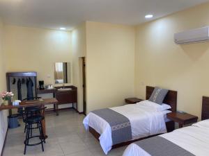 La GaritaにあるVilla Garita Innのベッド2台とデスクが備わるホテルルームです。