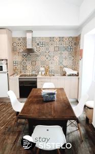uma cozinha com uma mesa de madeira e cadeiras brancas em Casa do Ferreiro em Sistelo